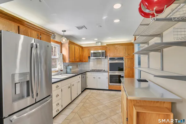 a kitchen with granite countertop a refrigerator oven a sink dishwasher and white cabinets with wooden floor