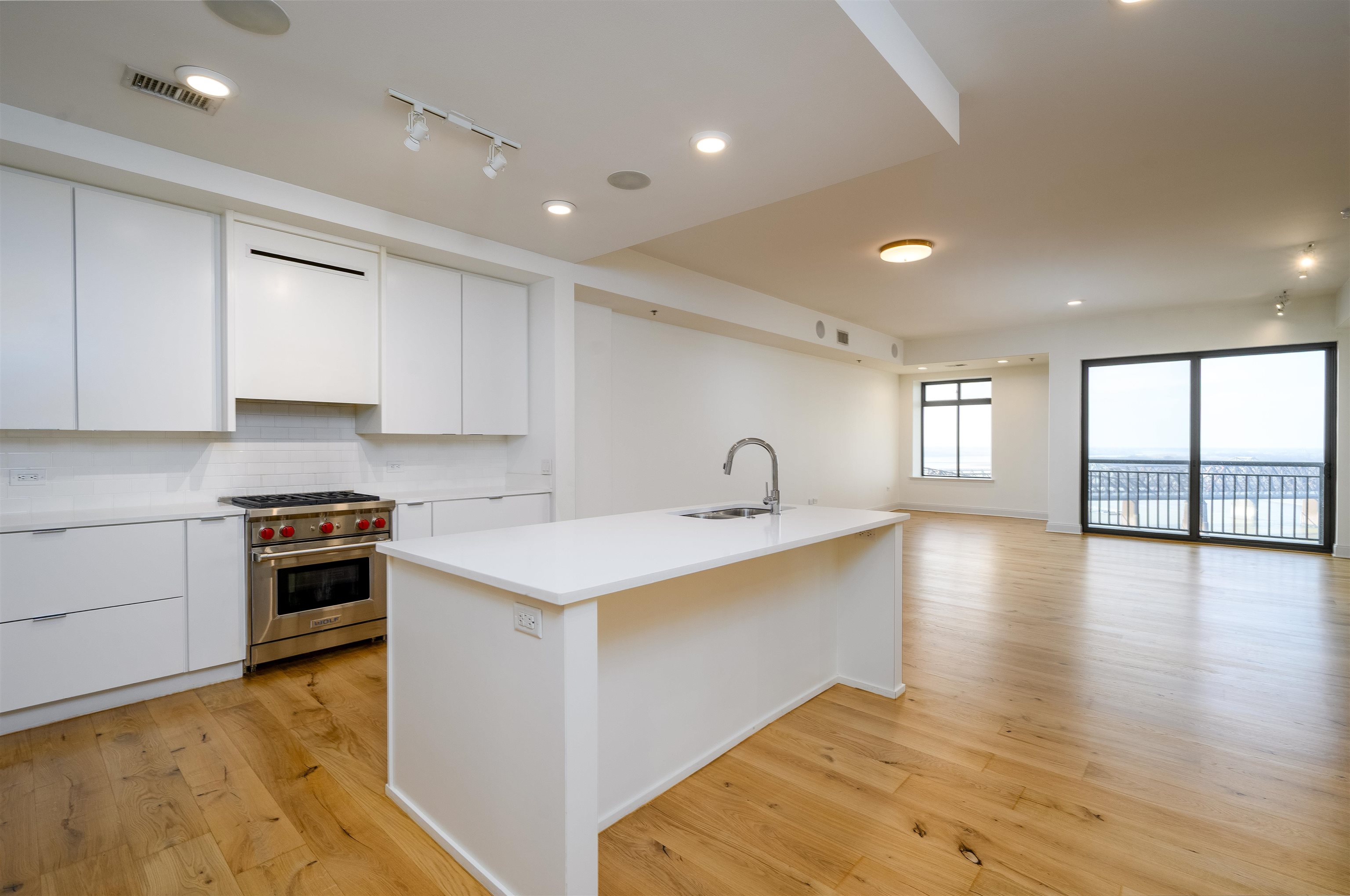 717 Riverside Drive, Unit 1506 Memphis, TN 38103 - Photo 4 of 38 a large kitchen with stainless steel appliances granite countertop a stove a sink a refrigerator and white cabinets with wooden floor