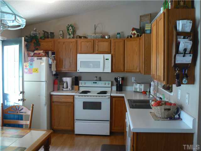 1723 Bahama Road Bahama, NC 27503 - Photo 7 of 14 a kitchen with refrigerator a stove a sink and a dining table with wooden floor