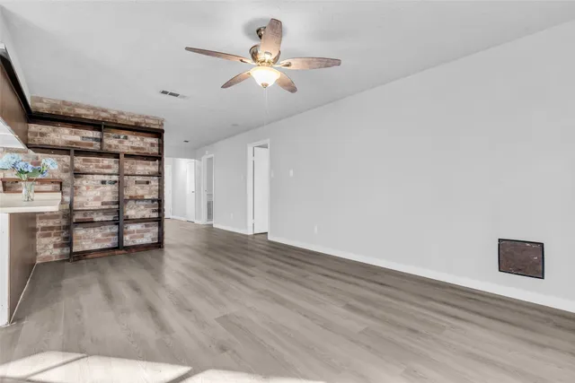 a view of an empty room with a window and wooden floor