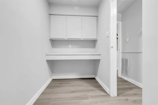 an empty room with wooden floor chandelier fan and windows
