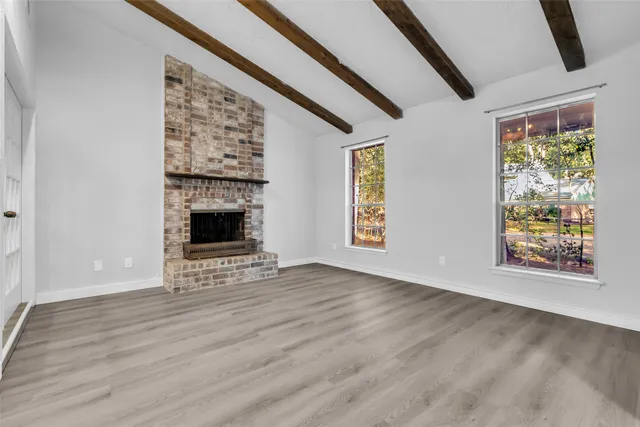 a view of an empty room with window and wooden floor