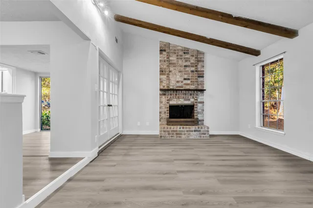 an empty room with windows and fireplace