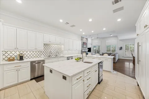 a kitchen that has a lot of white cabinets and stainless steel appliances