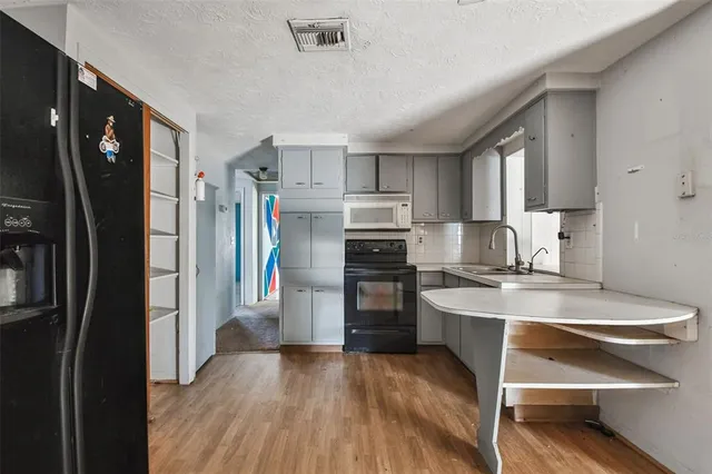 a view of kitchen with sink refrigerator and cabinets