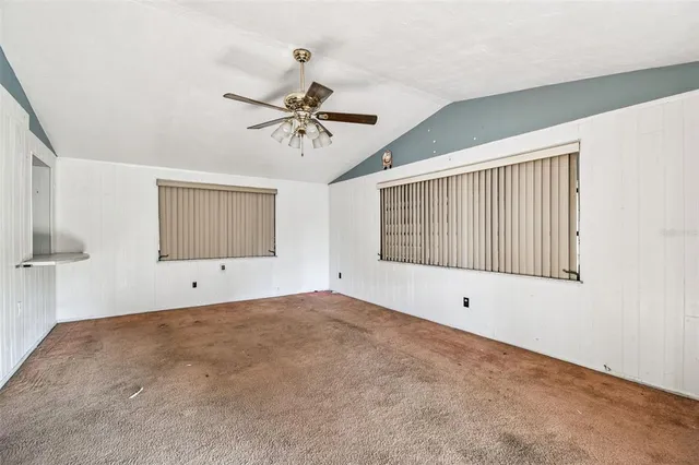 a view of an empty room with chandelier fan