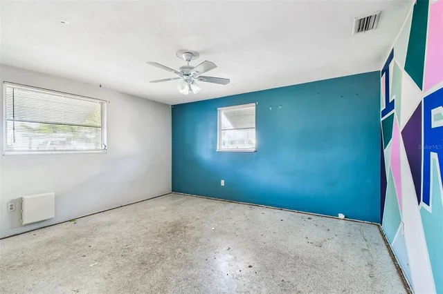 an empty room with windows and ceiling fan