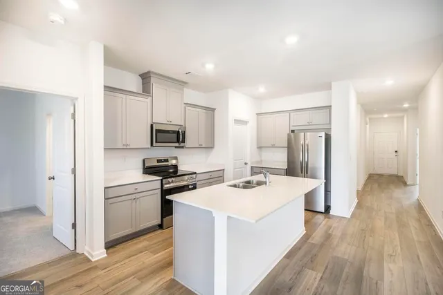 a kitchen with a sink a counter top space stainless steel appliances and cabinets