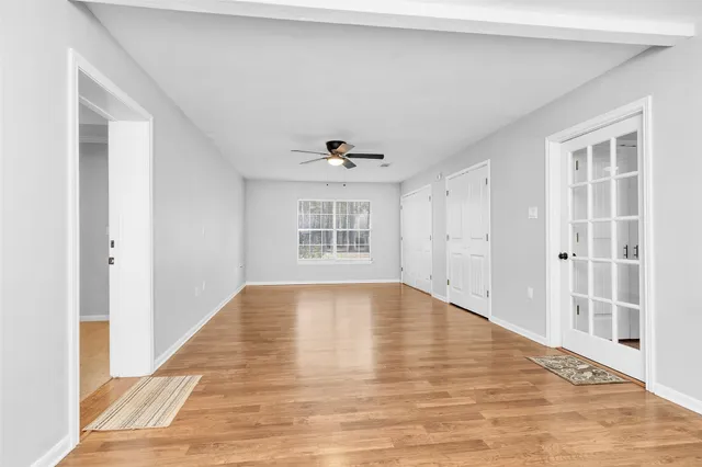 a view of empty room with wooden floor and fan