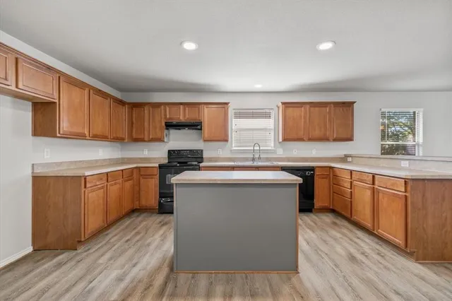 a kitchen with stainless steel appliances granite countertop wooden cabinets a sink and dishwasher a stove with wooden floors