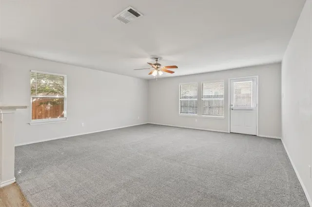 an empty room with windows and chandelier fan