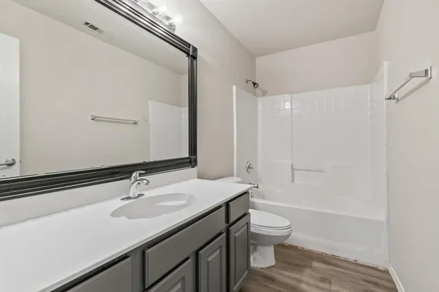 a bathroom with a granite countertop sink a toilet and shower