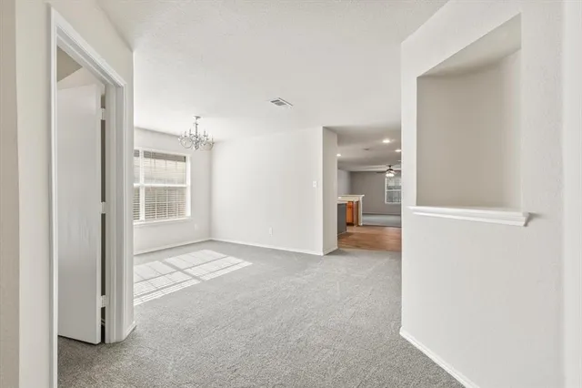 a view of an empty room with kitchen and a window