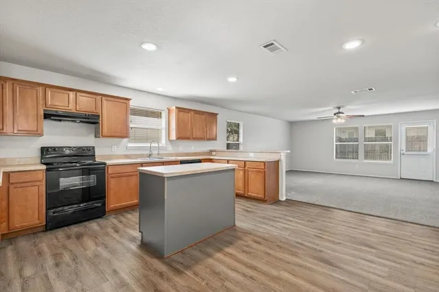a kitchen with stainless steel appliances kitchen island granite countertop a stove a sink and a refrigerator