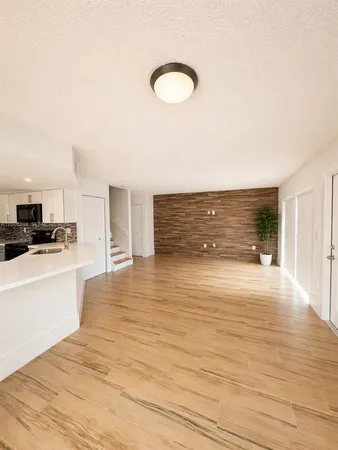 a view of kitchen and empty room with wooden floor