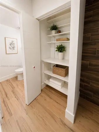 a view of hallway with wooden floor and cabinet