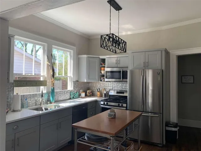 a kitchen with stainless steel appliances a sink a stove a refrigerator and cabinets