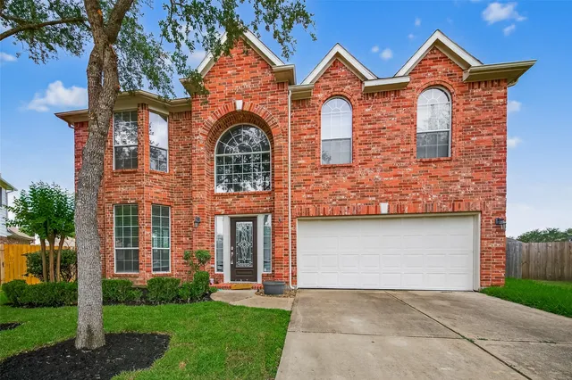 front view of brick house with a yard and a palm tree