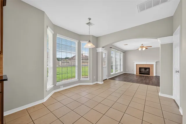 a view of an empty room with window and chandelier fan