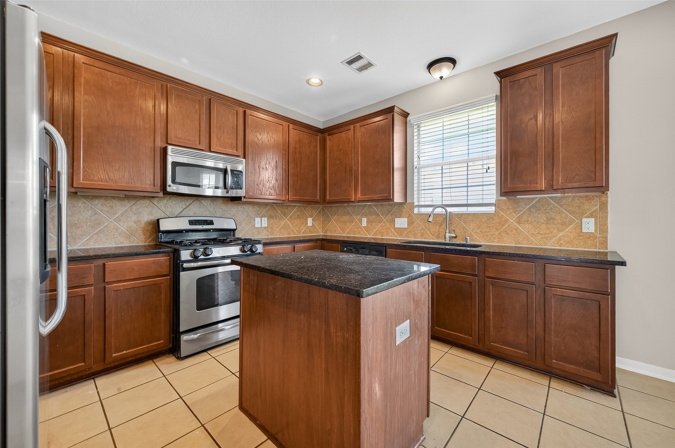 12902 Crystal Reef Court Pearland, TX 77584 - Photo 13 of 35 a kitchen with stainless steel appliances granite countertop a stove a sink and a microwave