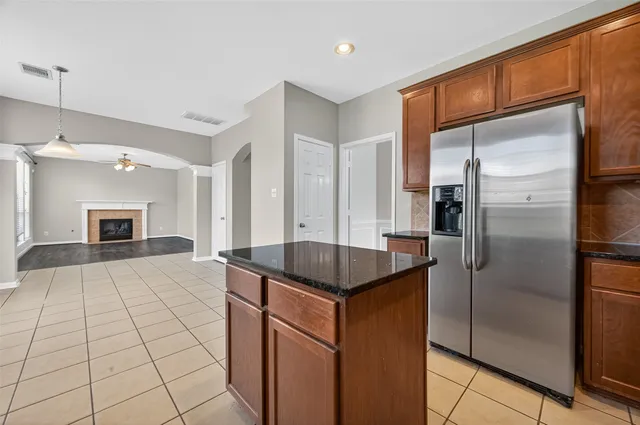 a kitchen with kitchen island granite countertop a refrigerator and a sink