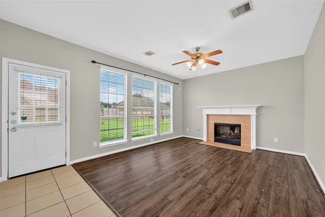 an empty room with windows fireplace and a chandelier fan