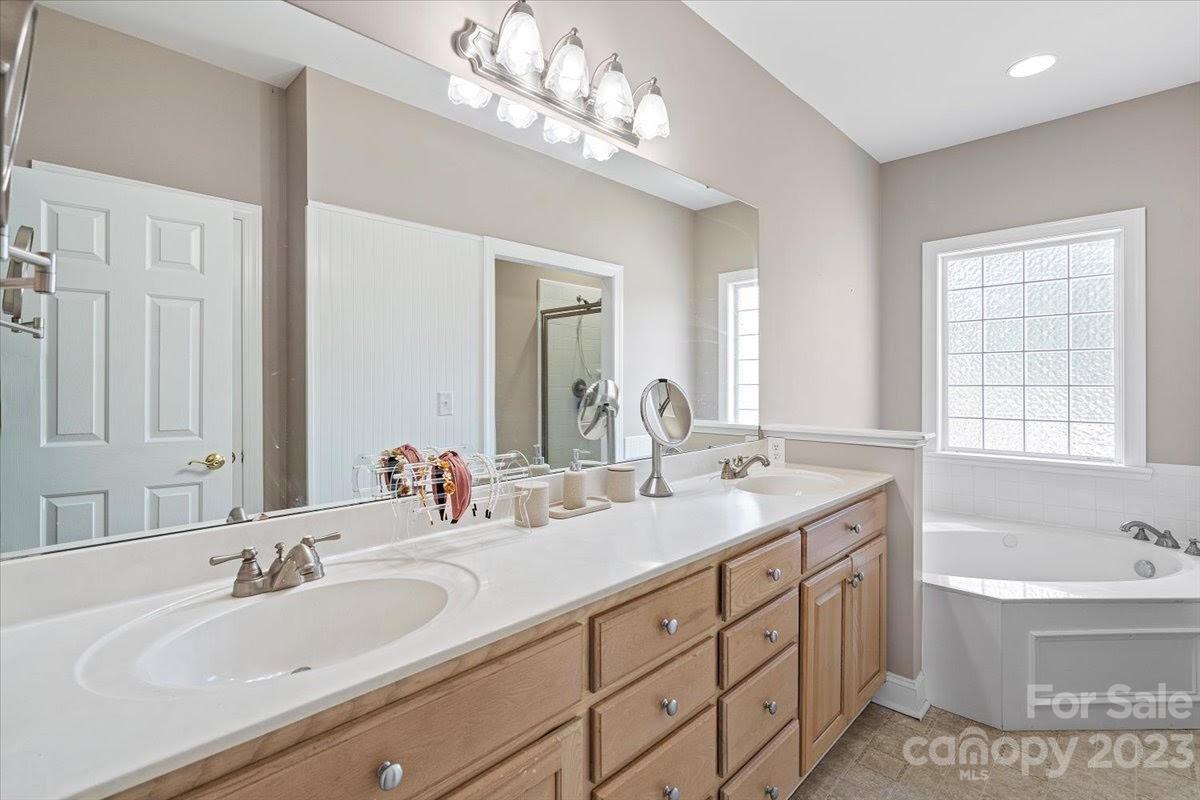 1531 Henry Smith Road Monroe, NC 28110 - Photo 17 of 31 a bathroom with double vanity sink a bathtub a mirror a vanity a lamp and window