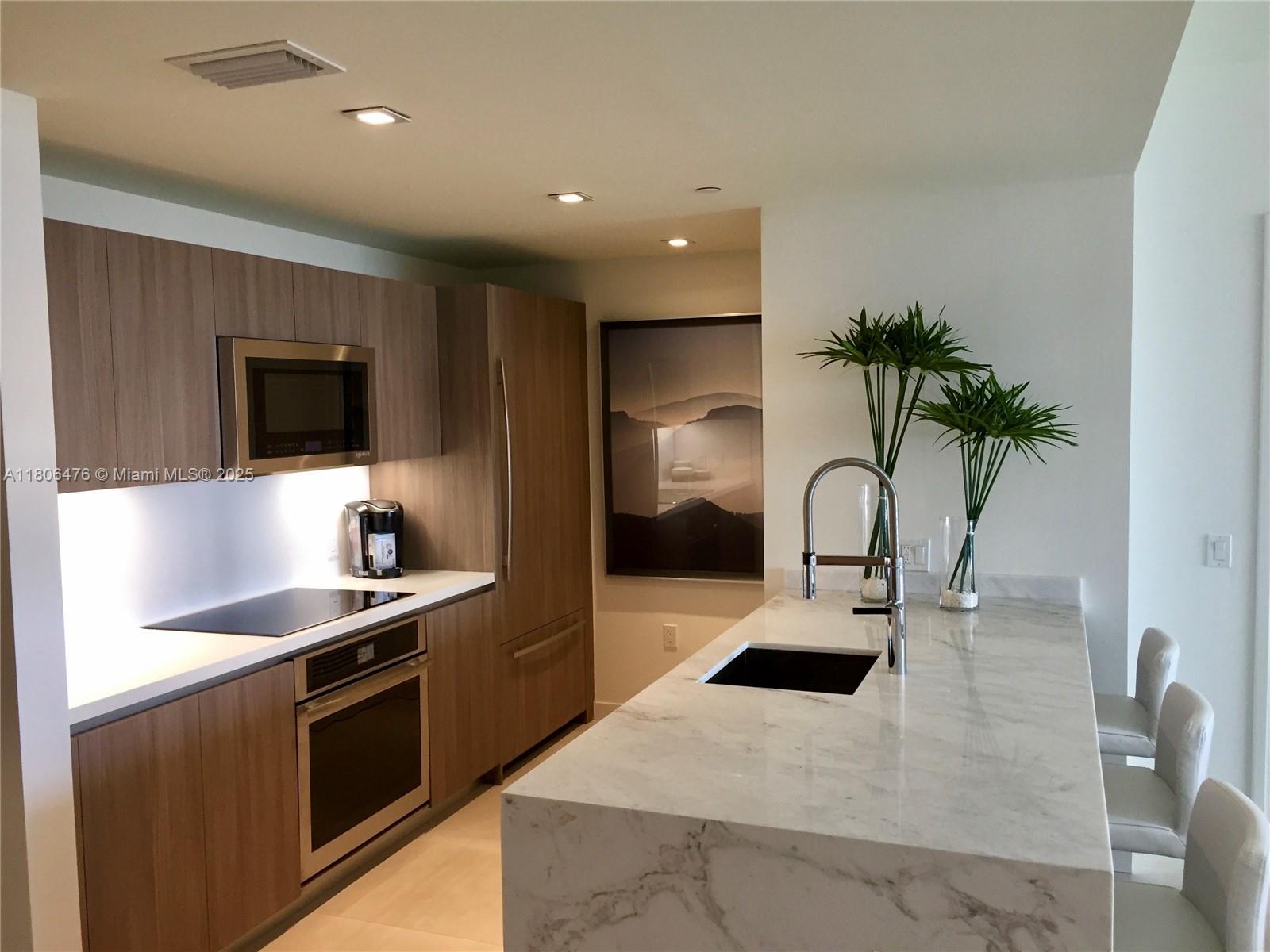 401 North Birch Road, Unit 505 Fort Lauderdale, FL 33304 - Photo 14 of 29 a kitchen with kitchen island a counter top a stove a sink and a refrigerator