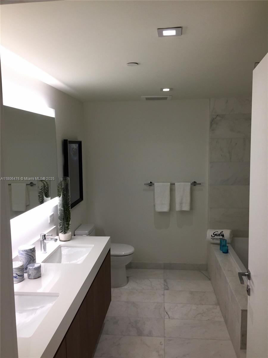 401 North Birch Road, Unit 505 Fort Lauderdale, FL 33304 - Photo 8 of 29 a bathroom with a double vanity sink a mirror and a toilet