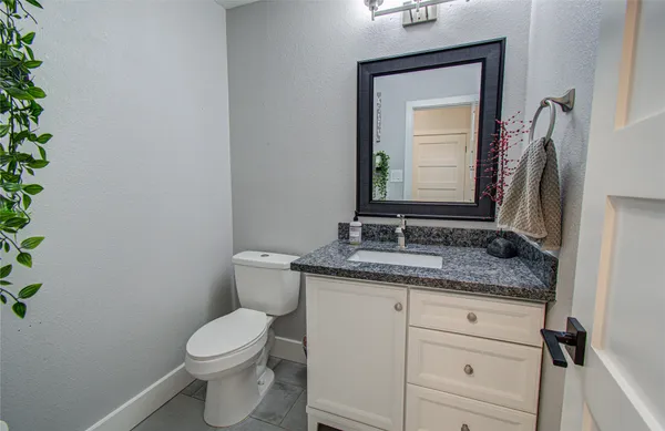 a bathroom with a granite countertop toilet sink and mirror