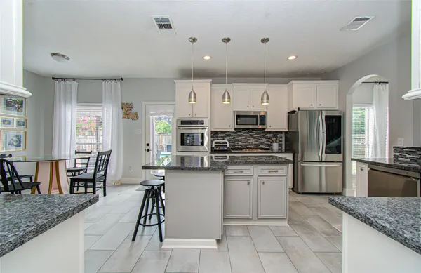 a kitchen with stainless steel appliances kitchen island granite countertop a stove refrigerator and cabinets