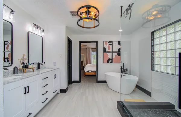 a spacious bathroom with a double vanity sink a mirror and a bathtub