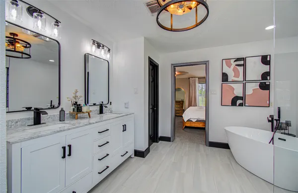 a bathroom with a two sinks a large mirror and a bathtub