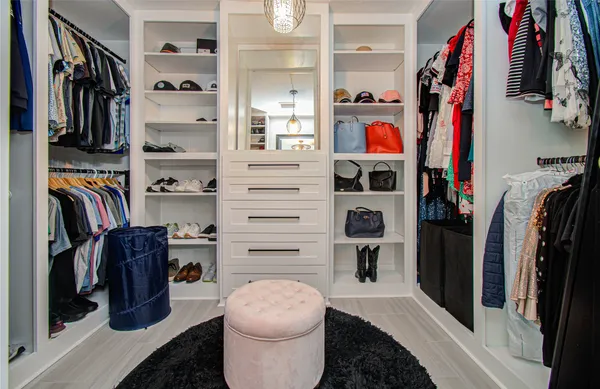a walk in closet with clothes and shoes