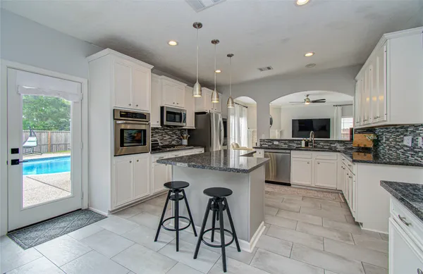 a large white kitchen with granite countertop lots of counter top space a sink and appliances