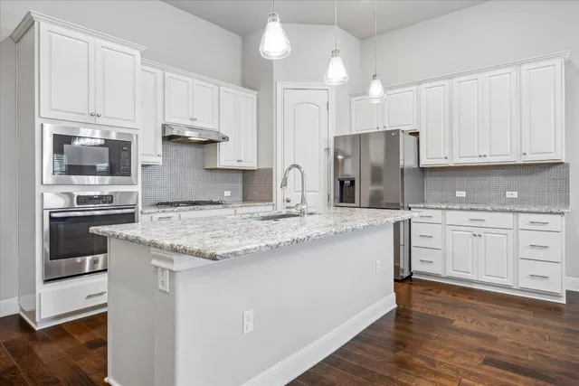 a kitchen with granite countertop white cabinets and stainless steel appliances