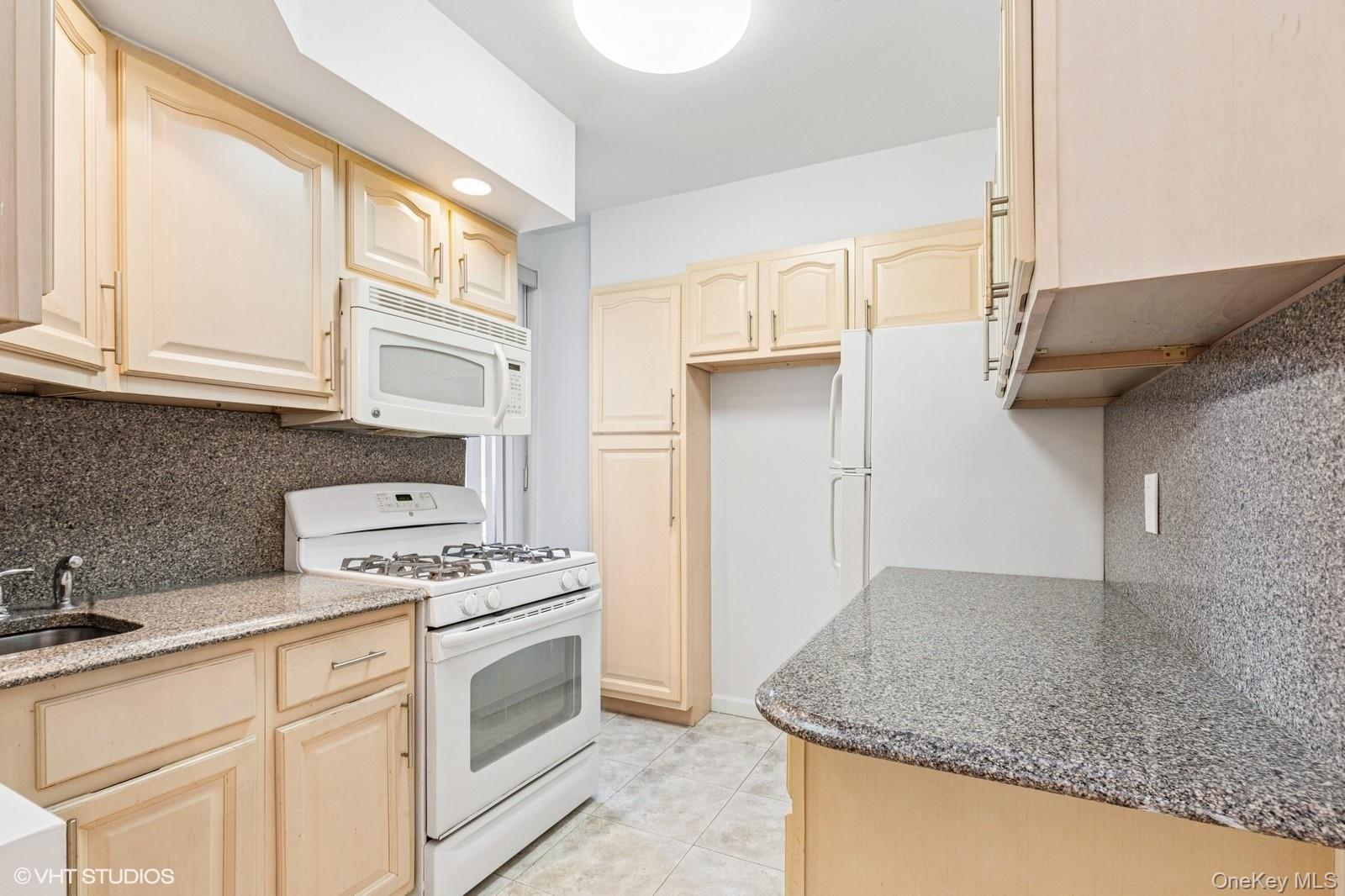 104-20 68th Drive, Unit B19 Queens, NY 11375 - Photo 7 of 15 a kitchen with granite countertop a sink stove and cabinets