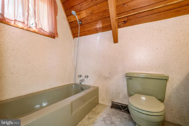 a bathroom with a granite countertop toilet sink and mirror