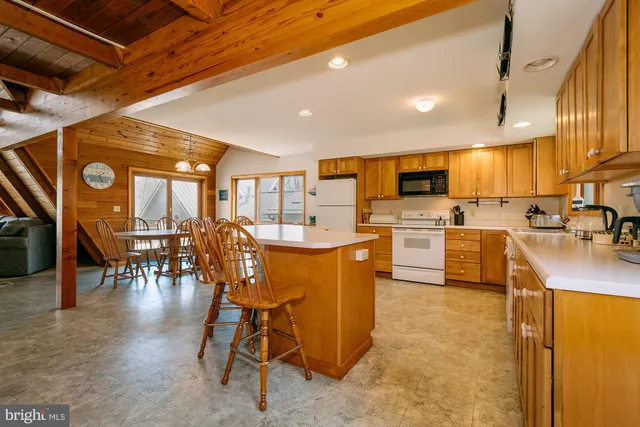 a kitchen with stainless steel appliances a stove a refrigerator a oven a dining table and chairs with wooden floor