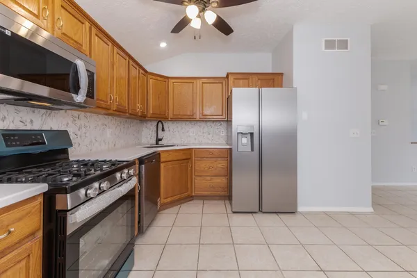 a kitchen with stainless steel appliances granite countertop a stove a sink and a refrigerator
