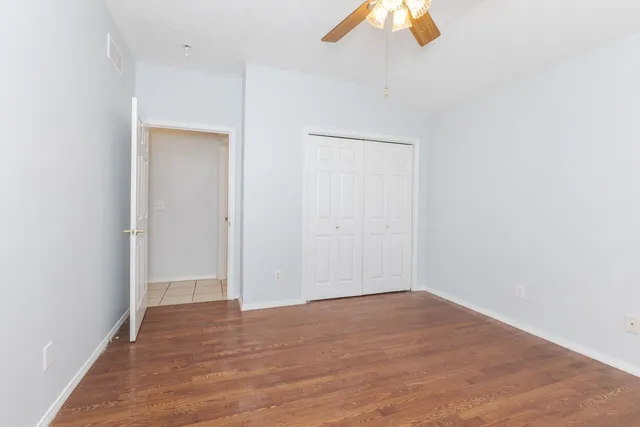an empty room with wooden floor closet and windows
