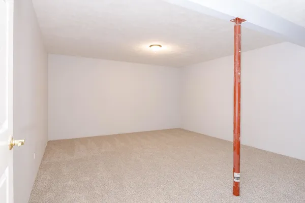 an empty room with wooden floor and fan