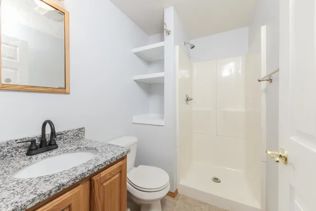 a bathroom with a granite countertop sink toilet and shower
