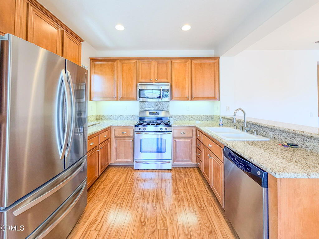 8262 Onyx Street Ventura, CA 93004 - Photo 9 of 33 a kitchen with stainless steel appliances granite countertop a refrigerator a sink dishwasher and a stove with wooden floor