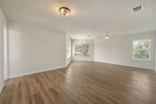 an empty room with wooden floor and windows