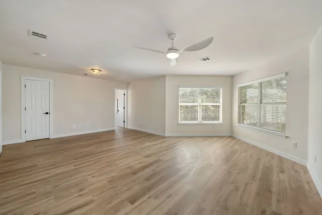 a view of an empty room with a window and wooden floor
