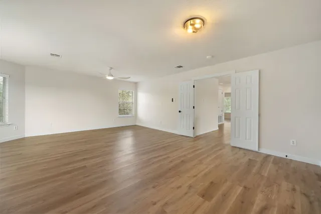 an empty room with wooden floor and windows