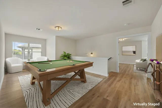 a room with furniture pool table wooden floor and windows