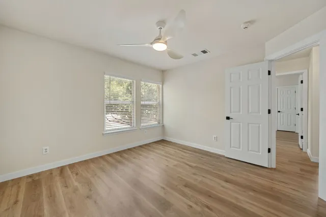 a view of an empty room with wooden floor and a window