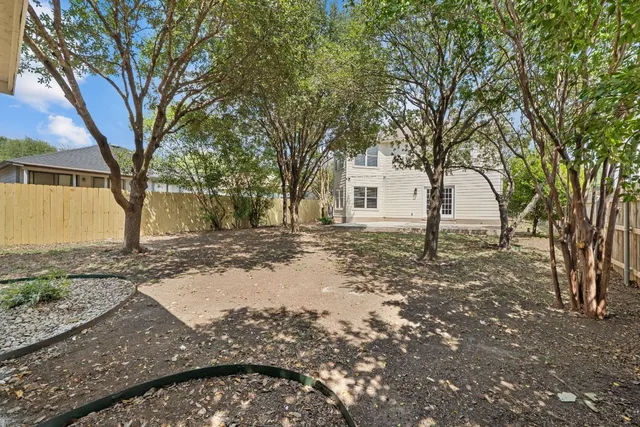 a backyard of a house with large trees and outdoor seating